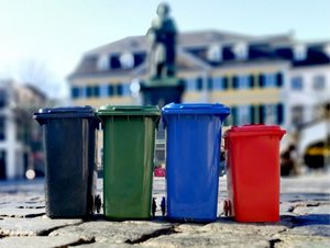 Tonnen im bonnorange Service Miniaturen der Restabfalltonne, Biotonne, Papiertonne und Roten Tonne von bonnorange vor dem Beethovendenkmal Bonn