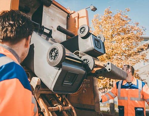 Abfallbehälter werden in einen bonnorange Müllwagen geleert.